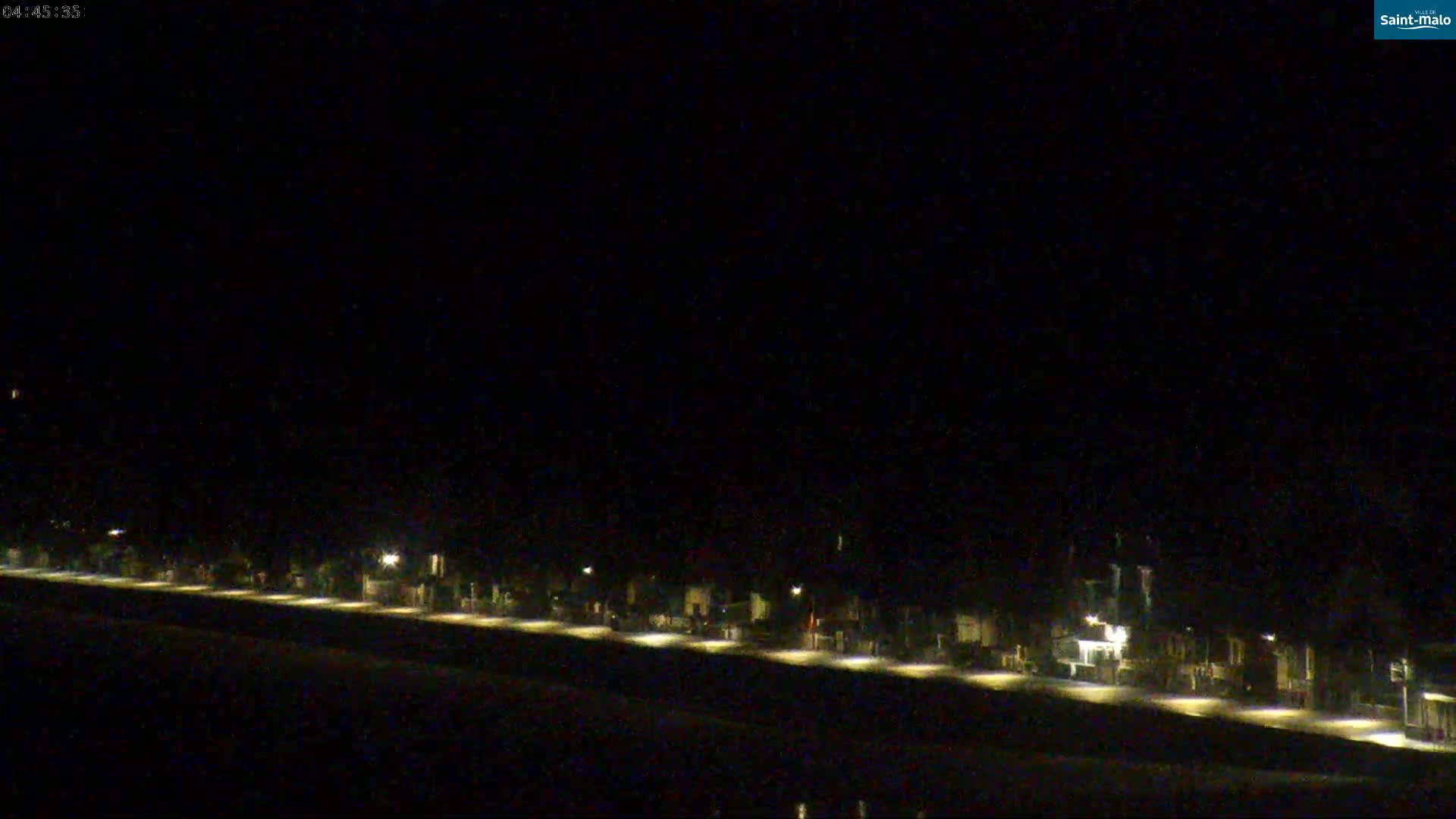 A long row of dimly lit buildings is visible at night under a dark sky.