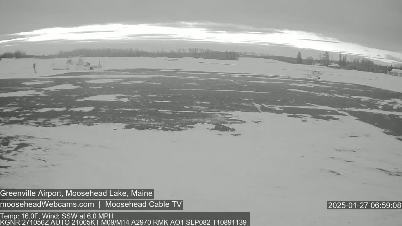 A snow-covered airfield is visible under an overcast sky, with a light wind blowing from the south-southwest.