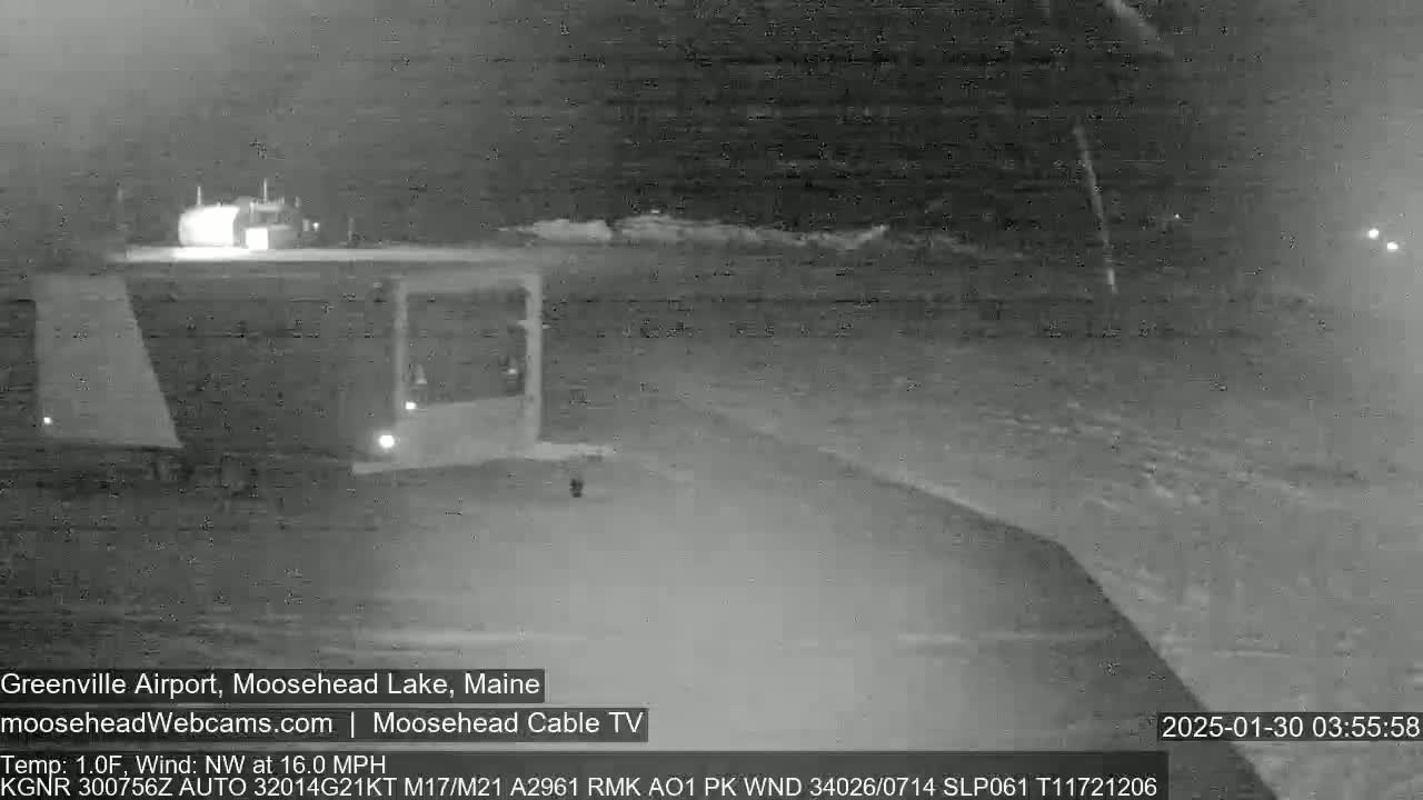 A nighttime, snow-covered airport runway is visible under a dark sky with a northwest wind at 16 mph.