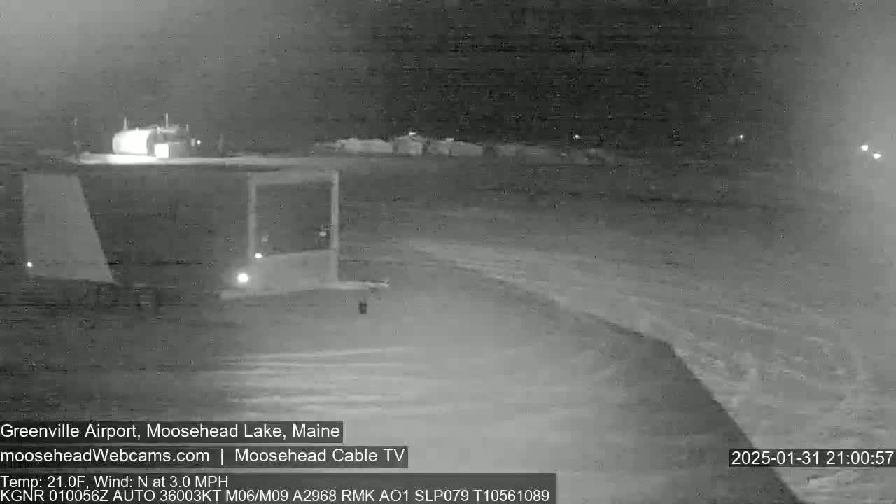 A nighttime, low-light view of a snow-covered airport with a slight north wind.