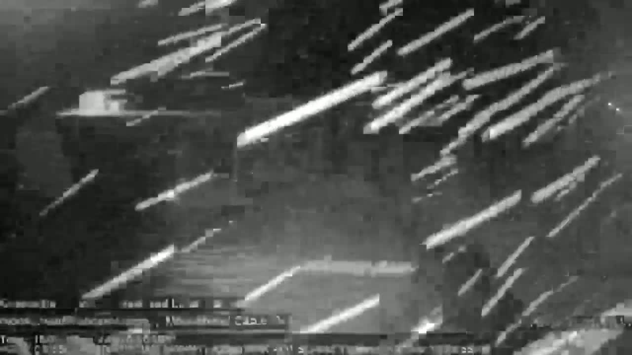 A dark, blurry image shows streaks of light against a dark background, possibly depicting a meteor shower at night.