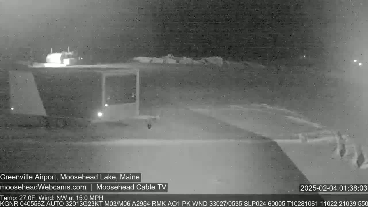 A nighttime, low-light view of a mostly empty airport tarmac with a northwest wind at 15 mph and a temperature of 27 degrees Fahrenheit.
