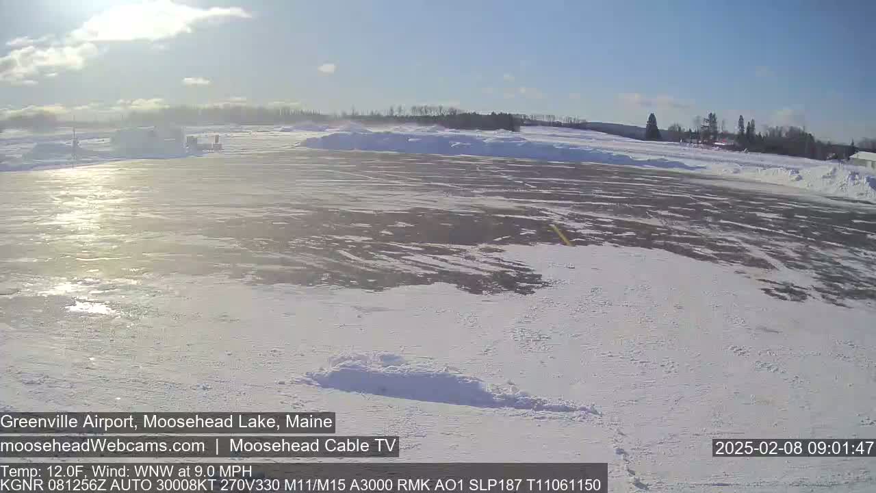 A snow-covered airfield is visible under a mostly sunny sky.