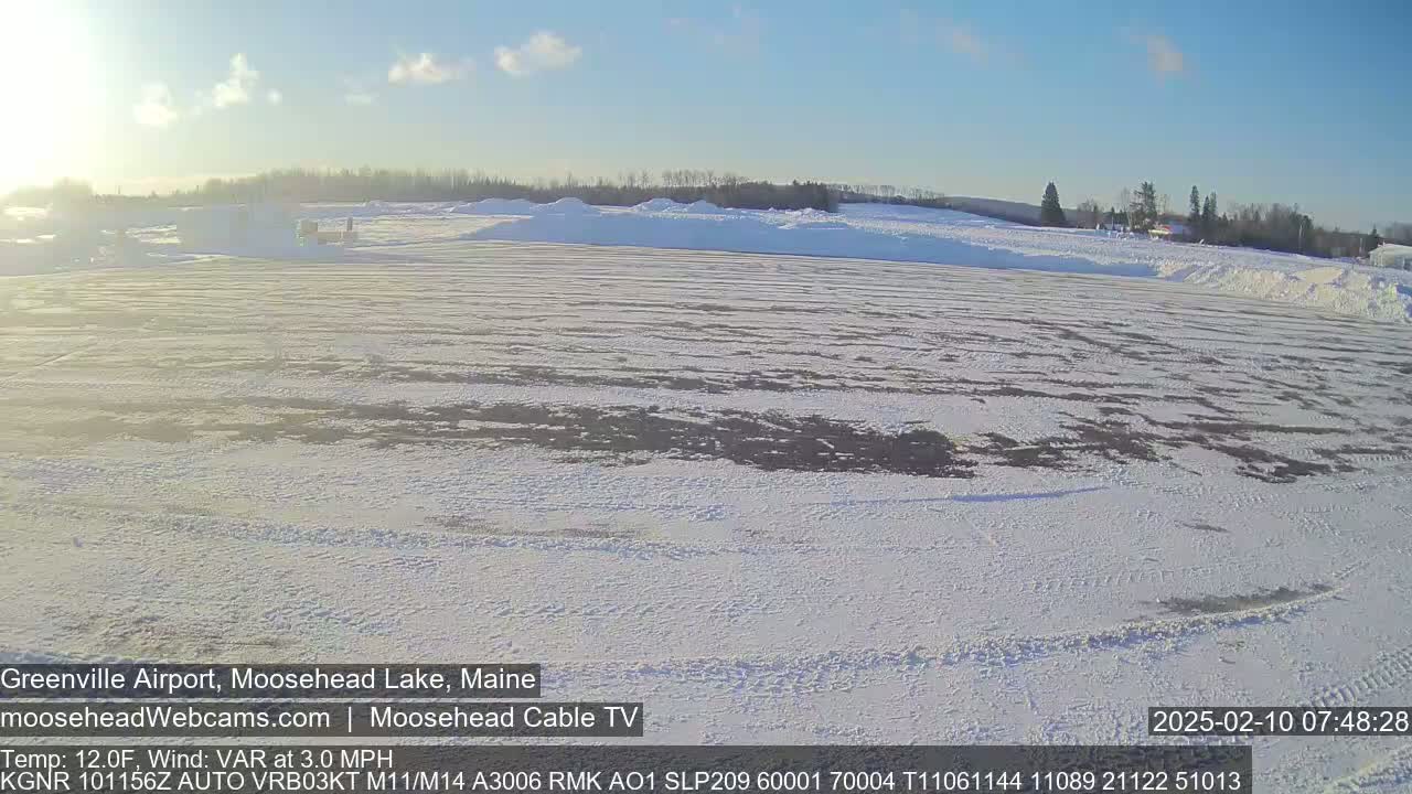 A snow-covered airfield is visible under a mostly clear, bright sky.