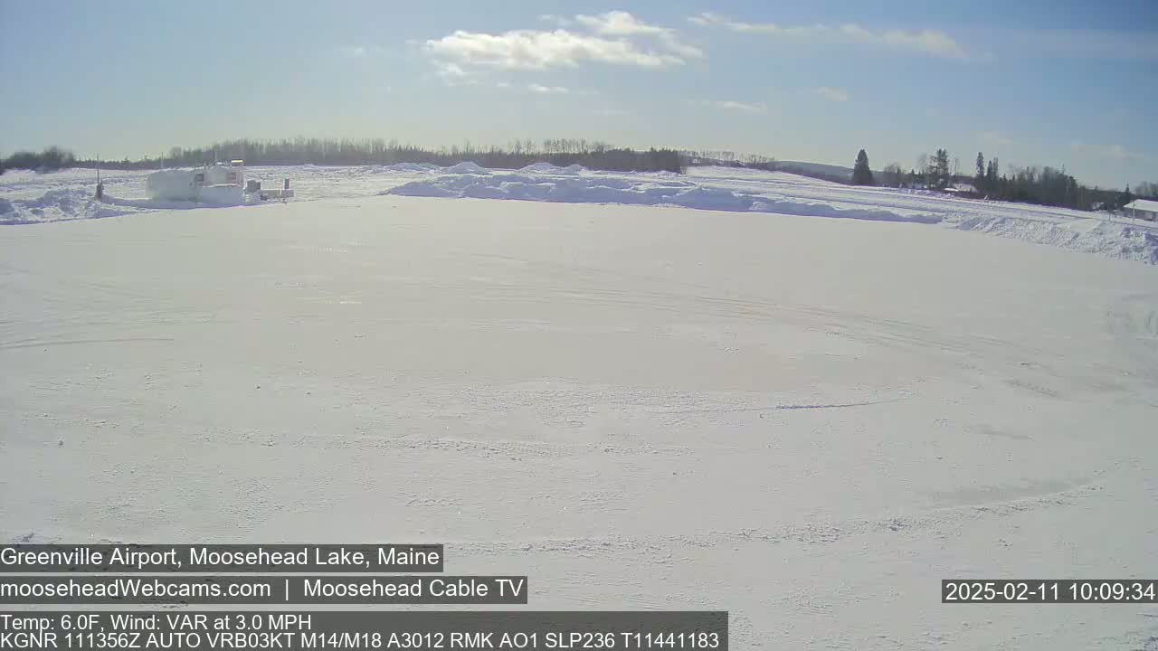 A snow-covered airfield is visible under a mostly clear sky.