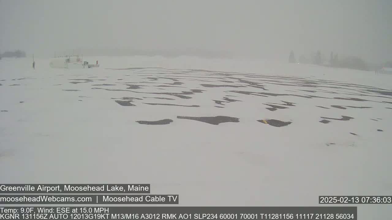 A snow-covered airfield is visible under hazy, snowy conditions.