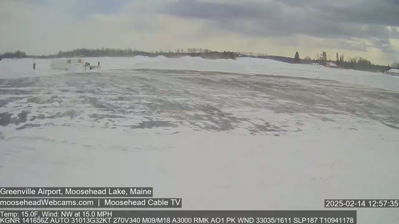 A snow-covered airfield is visible under a cloudy sky with a northwest wind.