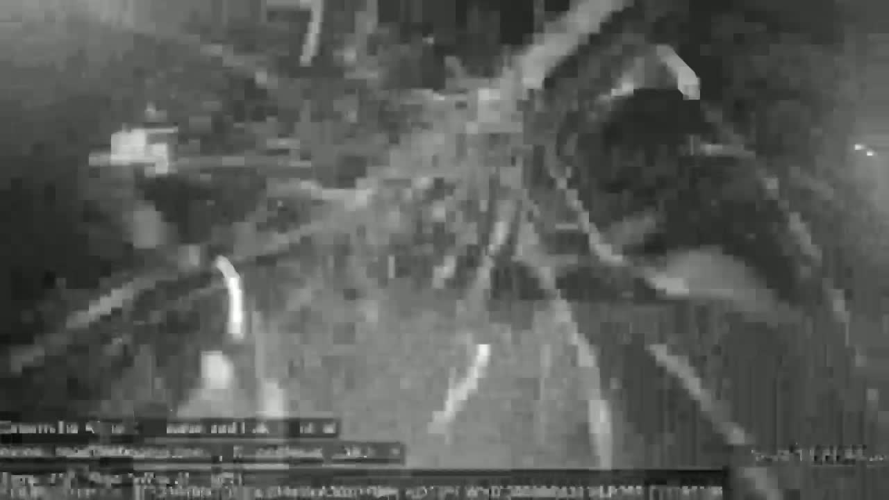 A grainy, low-light video shows a chaotic scene of what appears to be debris and possibly machinery moving in a dark, possibly nighttime environment.