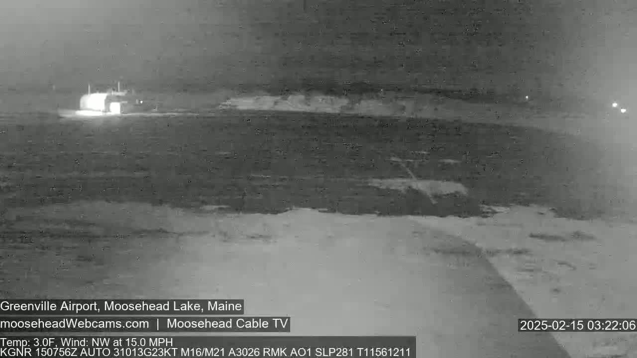 A nighttime, low-light image shows a body of water with a building faintly visible in the distance under a dark, overcast sky with a northwest wind of 15 mph and a temperature of 3 degrees Fahrenheit.