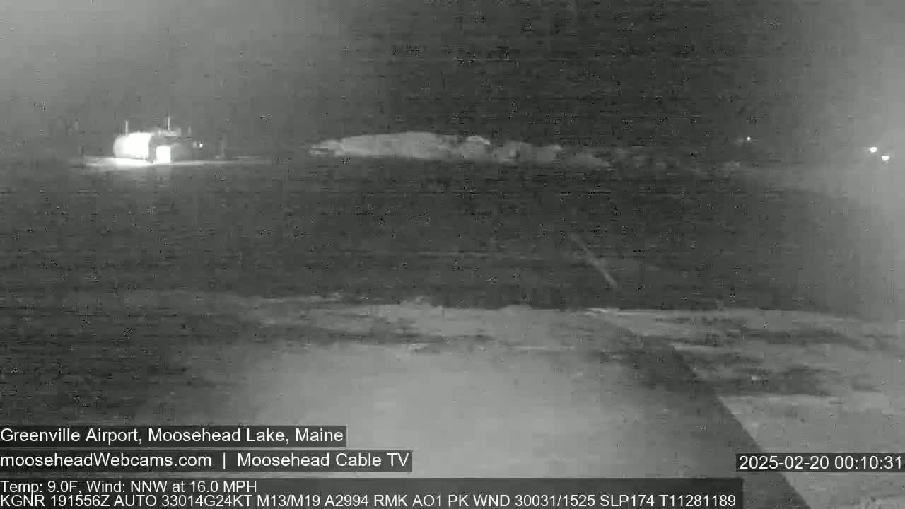 A nighttime, low-light view of a building near a snow-covered area, with a wind of 16 mph from the north-northwest.