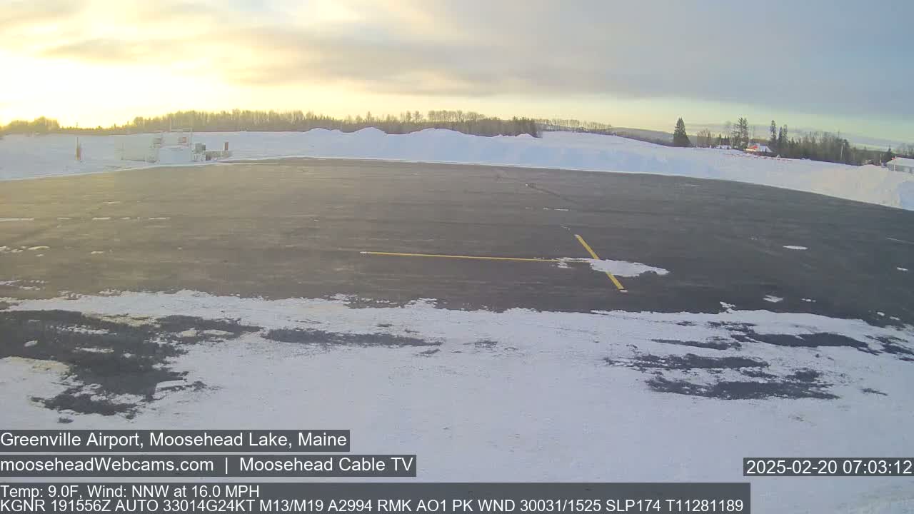 A mostly clear, cold morning shows a snow-covered tarmac and surrounding landscape at a small airport.