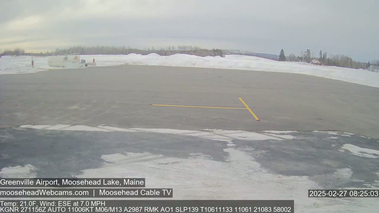 A mostly empty airport tarmac with patches of snow and ice under an overcast sky.