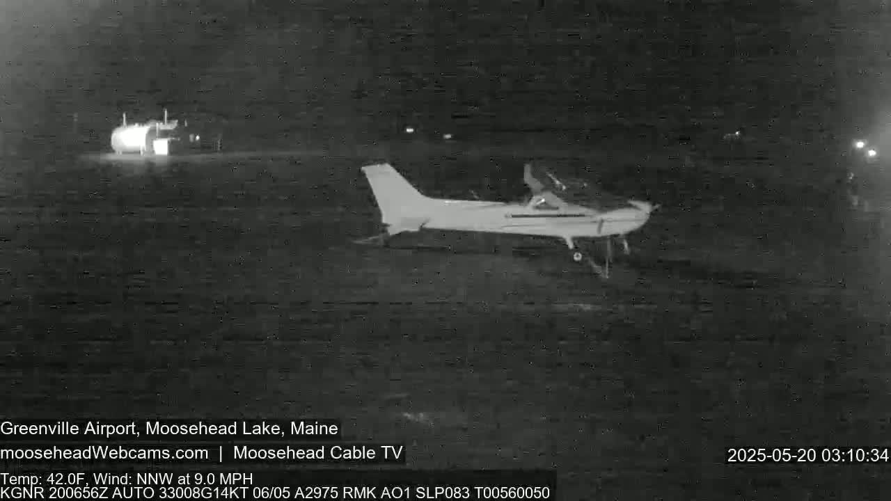 A small airplane is parked on an airfield at night, under a dark sky with a northwest wind.