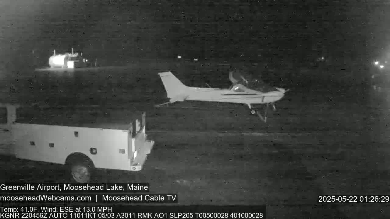 A small airplane is parked on a tarmac at night near a truck, under a clear sky with a temperature of 41°F and a 13 mph wind from the east-southeast.