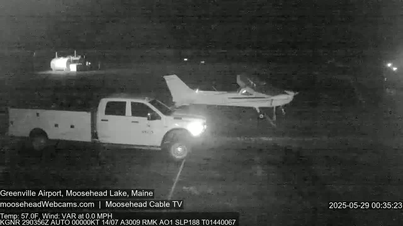 At night, a pickup truck is parked near a small airplane on a dark, paved surface.