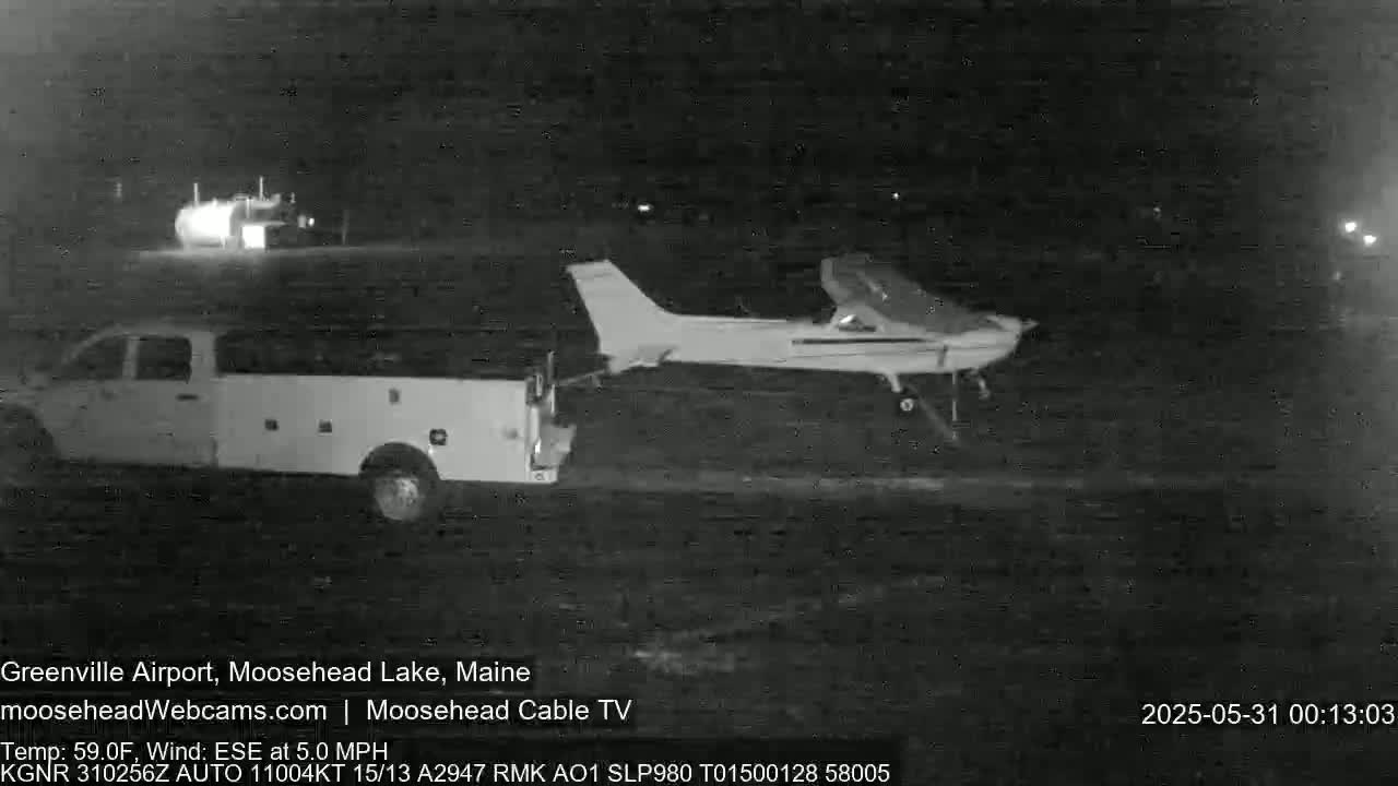 At night, a small airplane is being towed by a pickup truck on a tarmac.