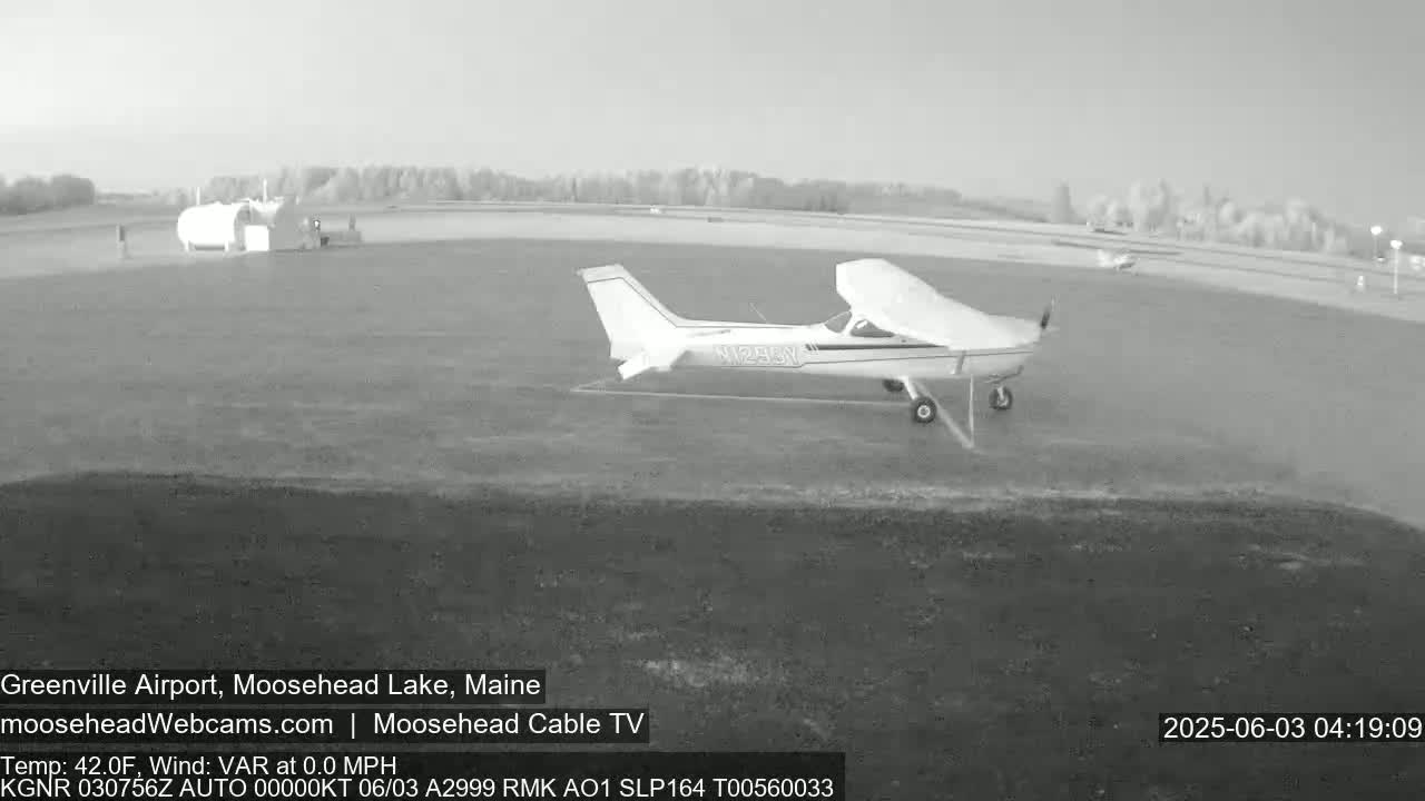 A small airplane is on a tarmac at an airport under a partly cloudy sky.
