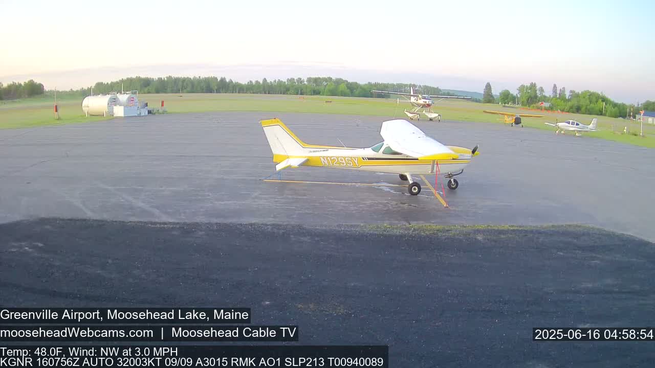 Several small airplanes are parked on a tarmac at an airport under a clear sky.