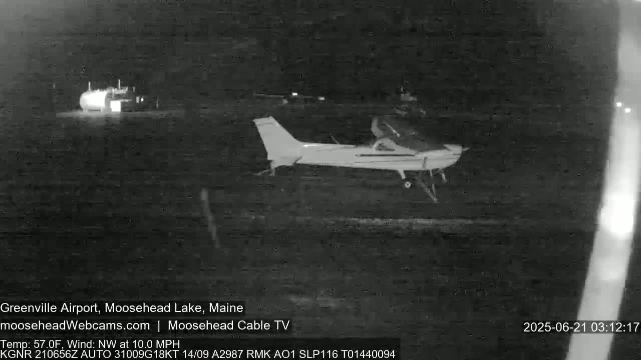 A small airplane sits on a dark tarmac at night under a clear sky with a northwest wind.