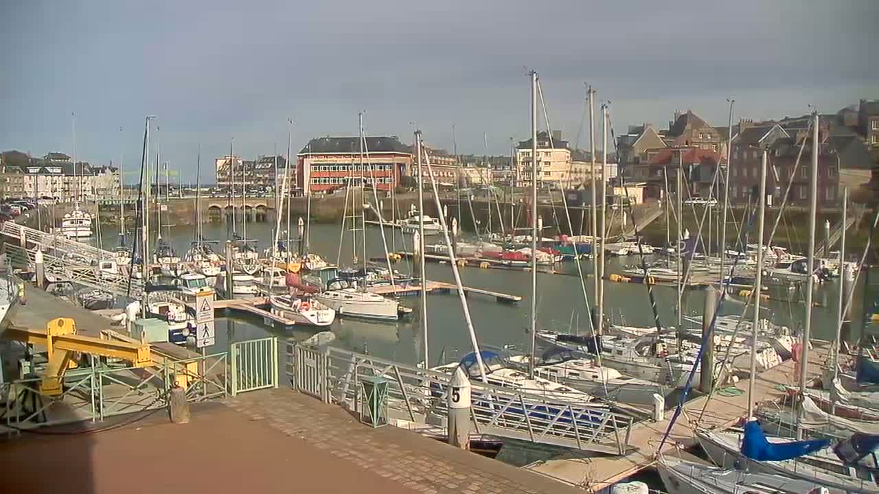A marina filled with sailboats and motorboats is seen on a partly sunny day.