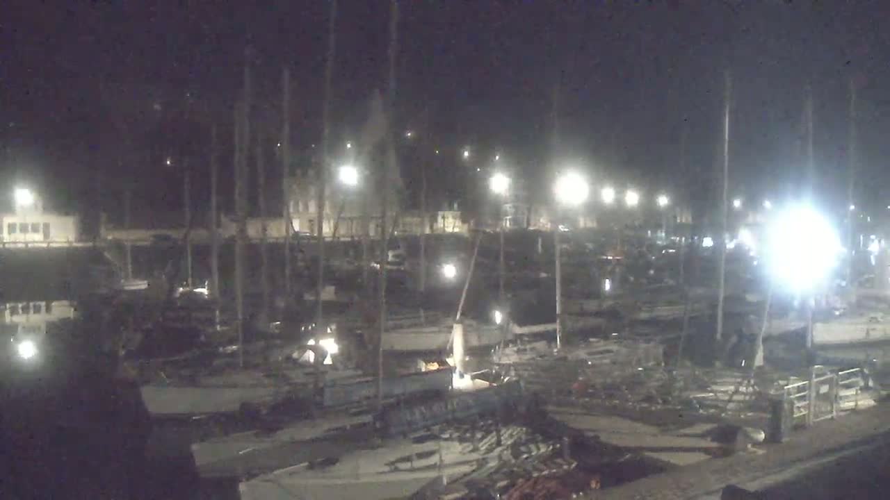 A nighttime view of a marina filled with numerous boats under artificial lights.