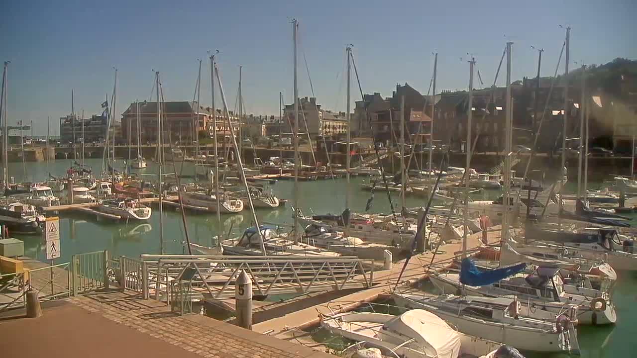 A marina filled with numerous sailboats and motorboats is seen on a sunny day.