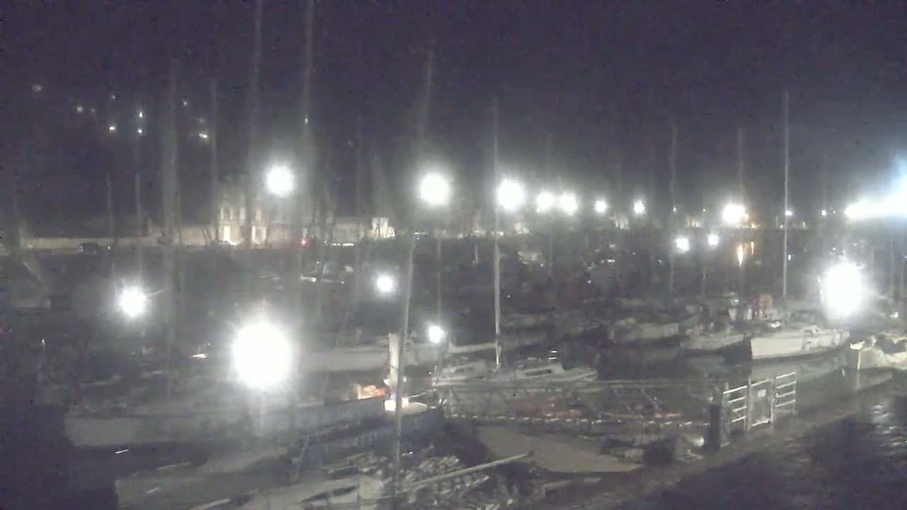 A nighttime view of a marina filled with boats under bright artificial lights.