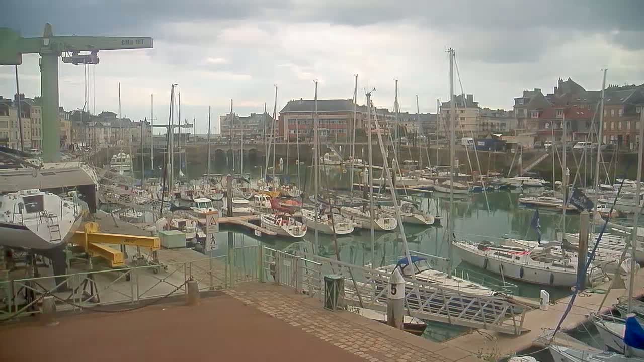 A marina filled with sailboats and motorboats is seen on an overcast day.