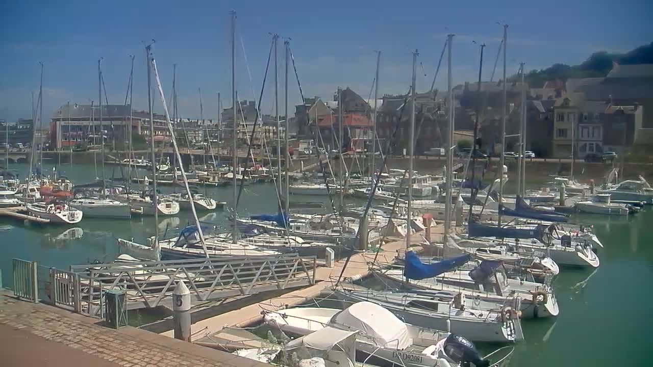 A marina filled with sailboats and motorboats on a sunny day.