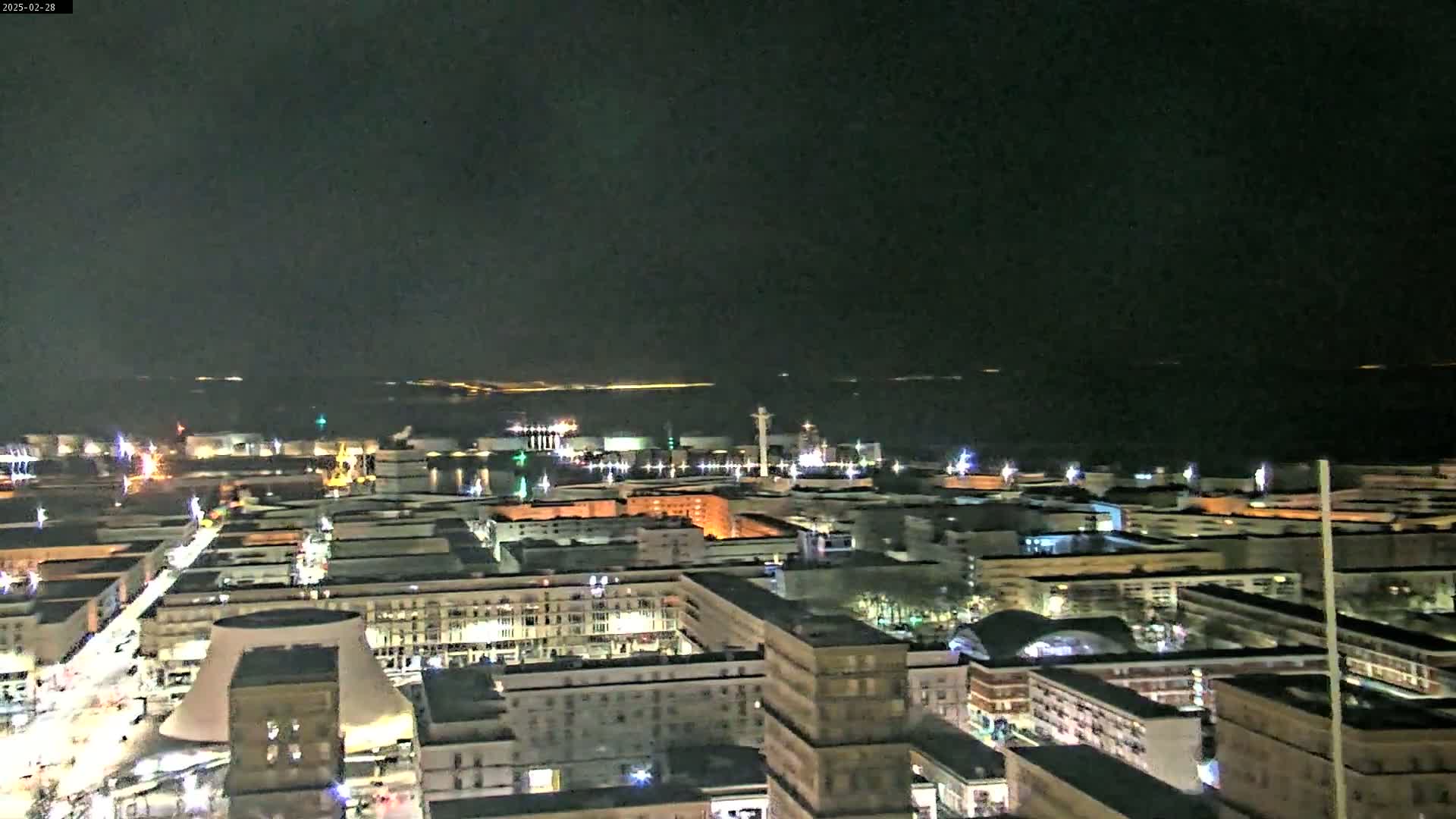 A nighttime aerial view of a city port, with a dark, clear sky above.
