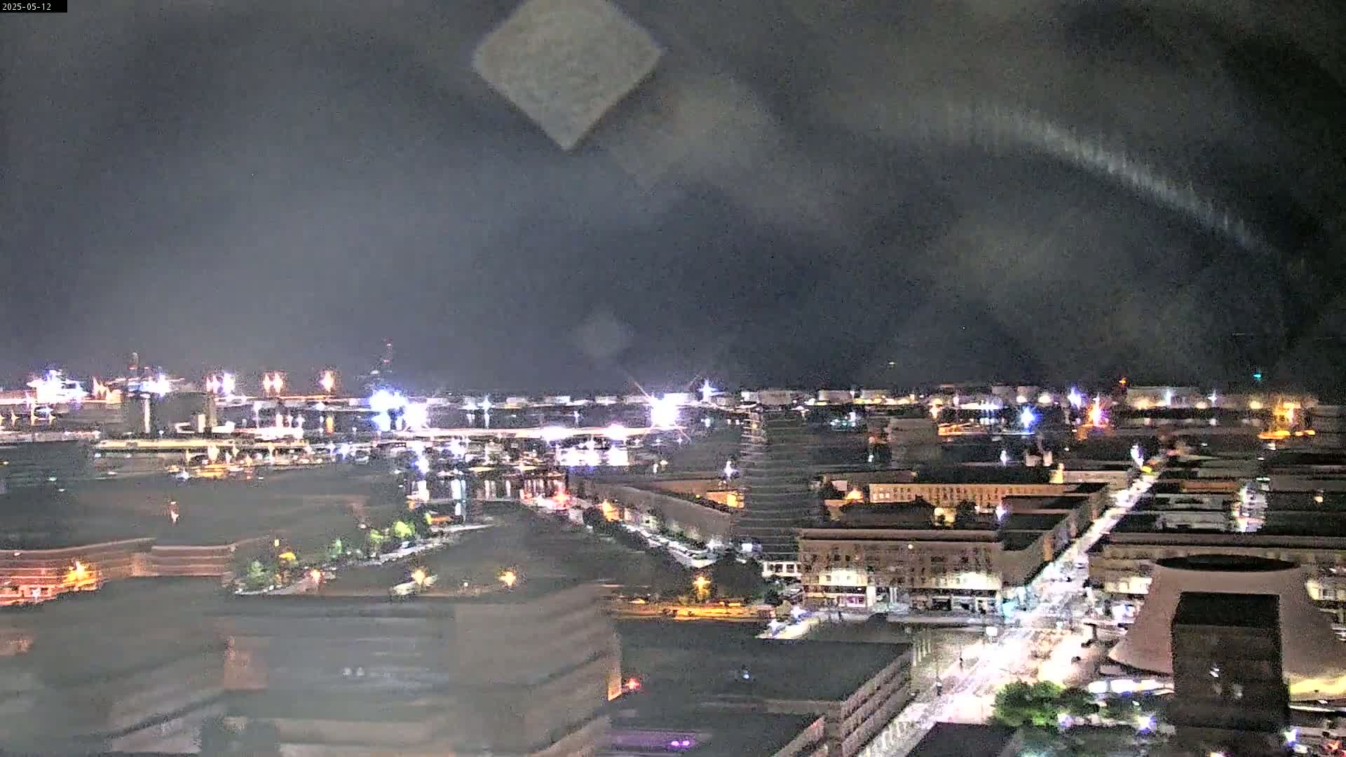 A nighttime, hazy view of a city skyline with illuminated buildings and streets.