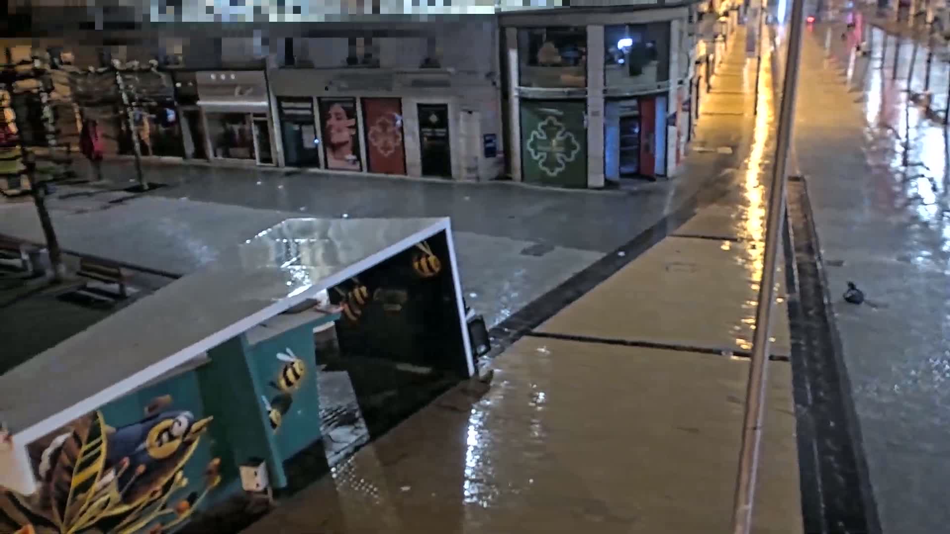 A flooded city street at night, with rain reflecting the lights from the buildings.