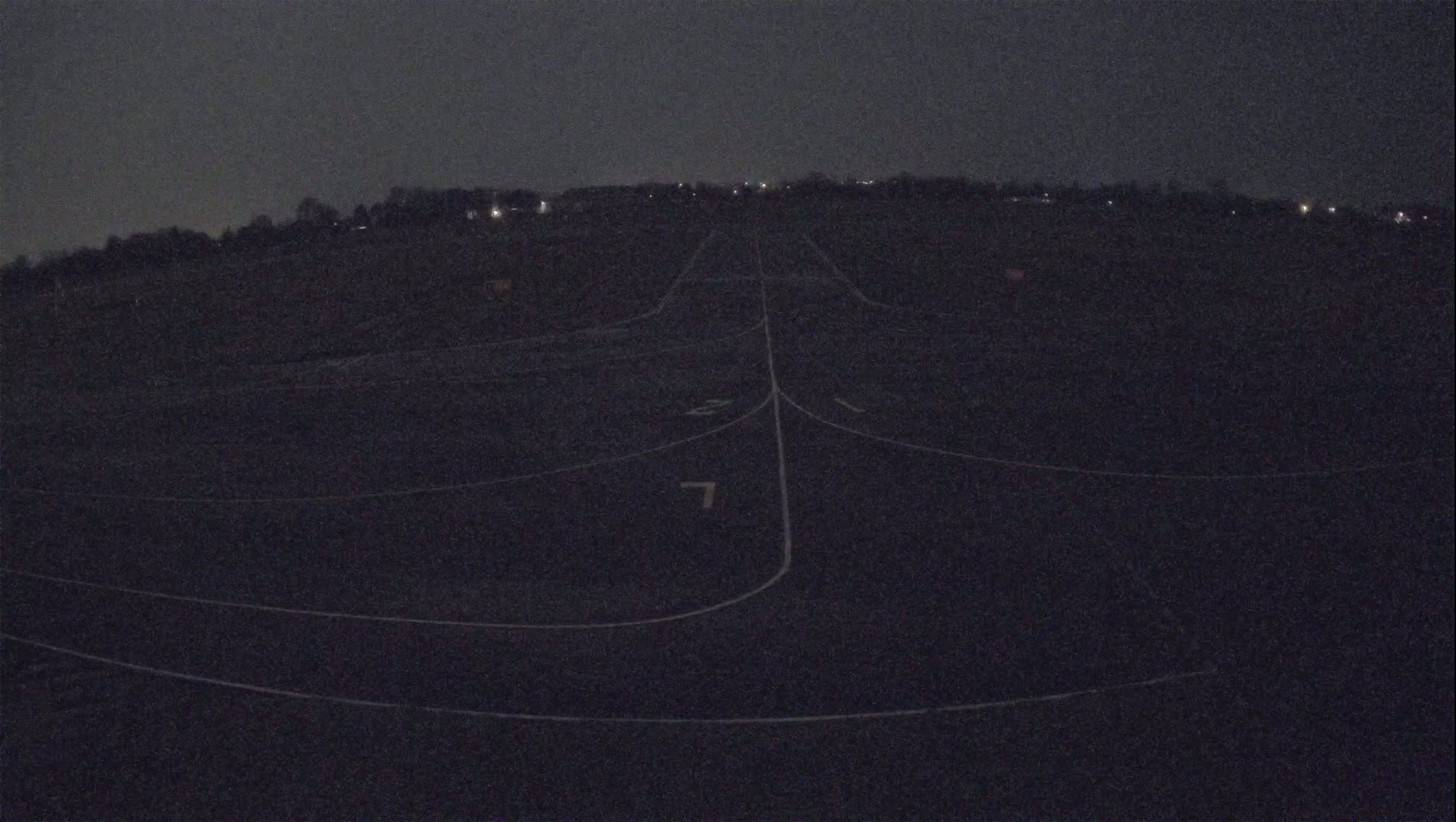A dark asphalt surface with white lane markings extends into the distance under a night sky.