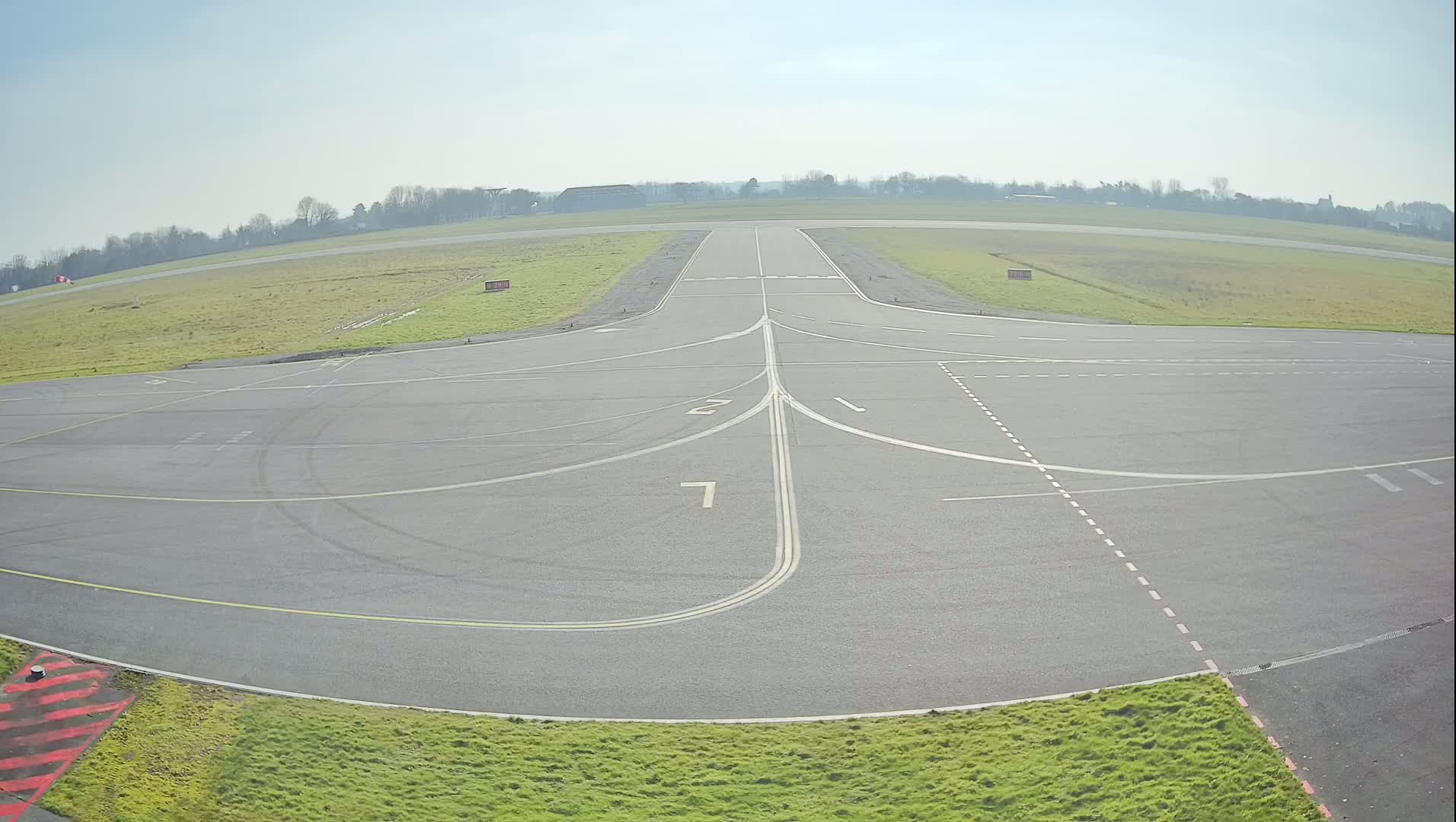 A paved airfield apron with painted lines and numbers, under a clear, bright sky.
