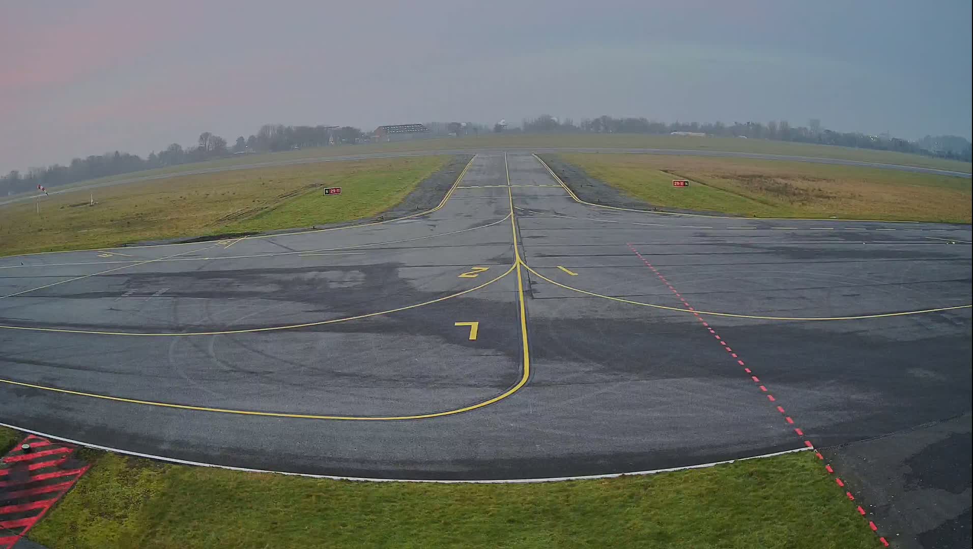 An empty airport tarmac with a runway extending into a foggy, overcast distance.