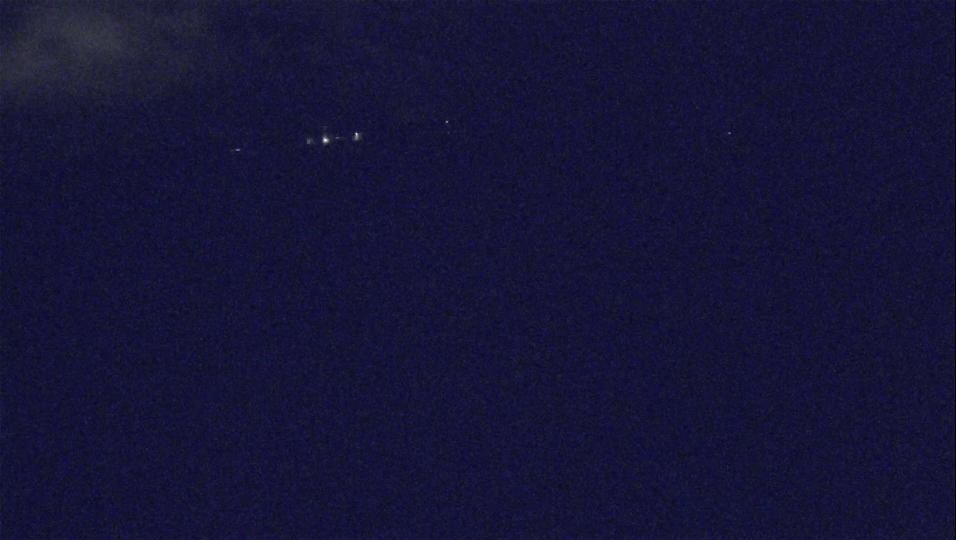 A dark night sky shows a few faint lights in the distance.
