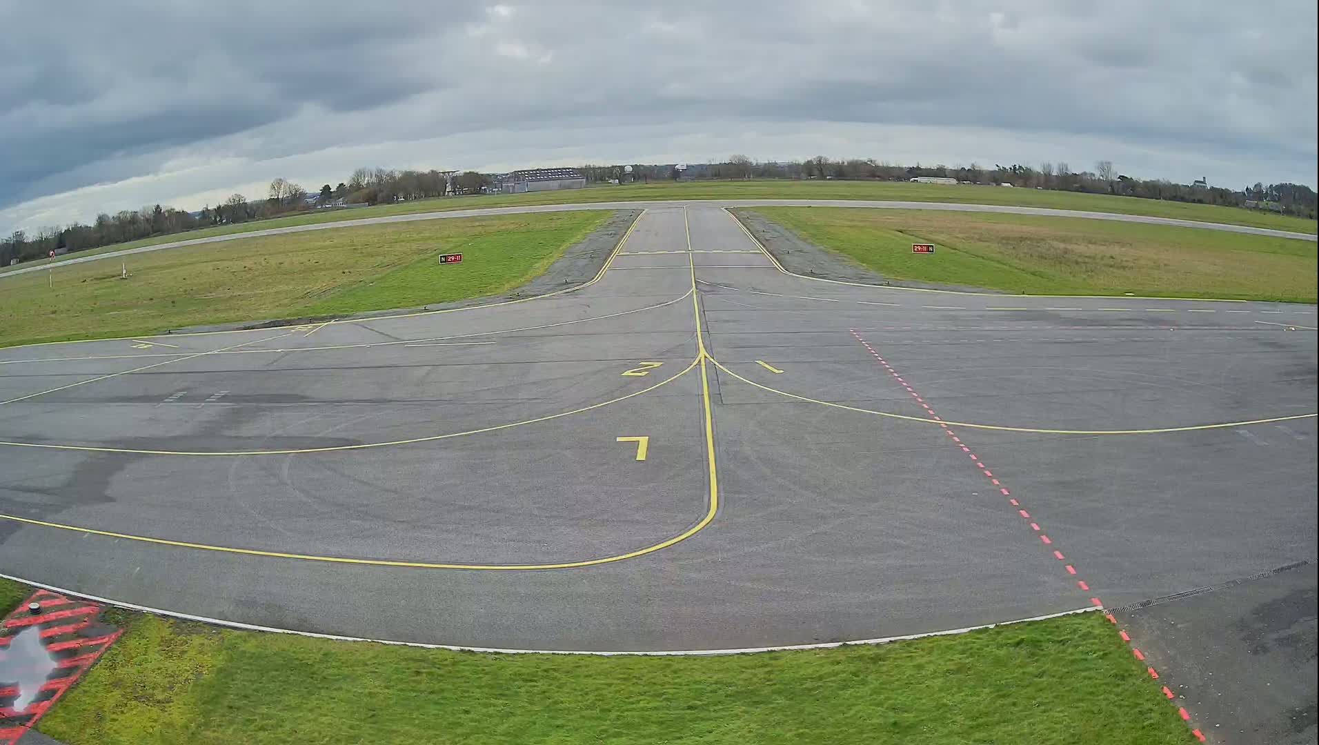 A tarmac airport runway and taxiway area is visible under an overcast sky.