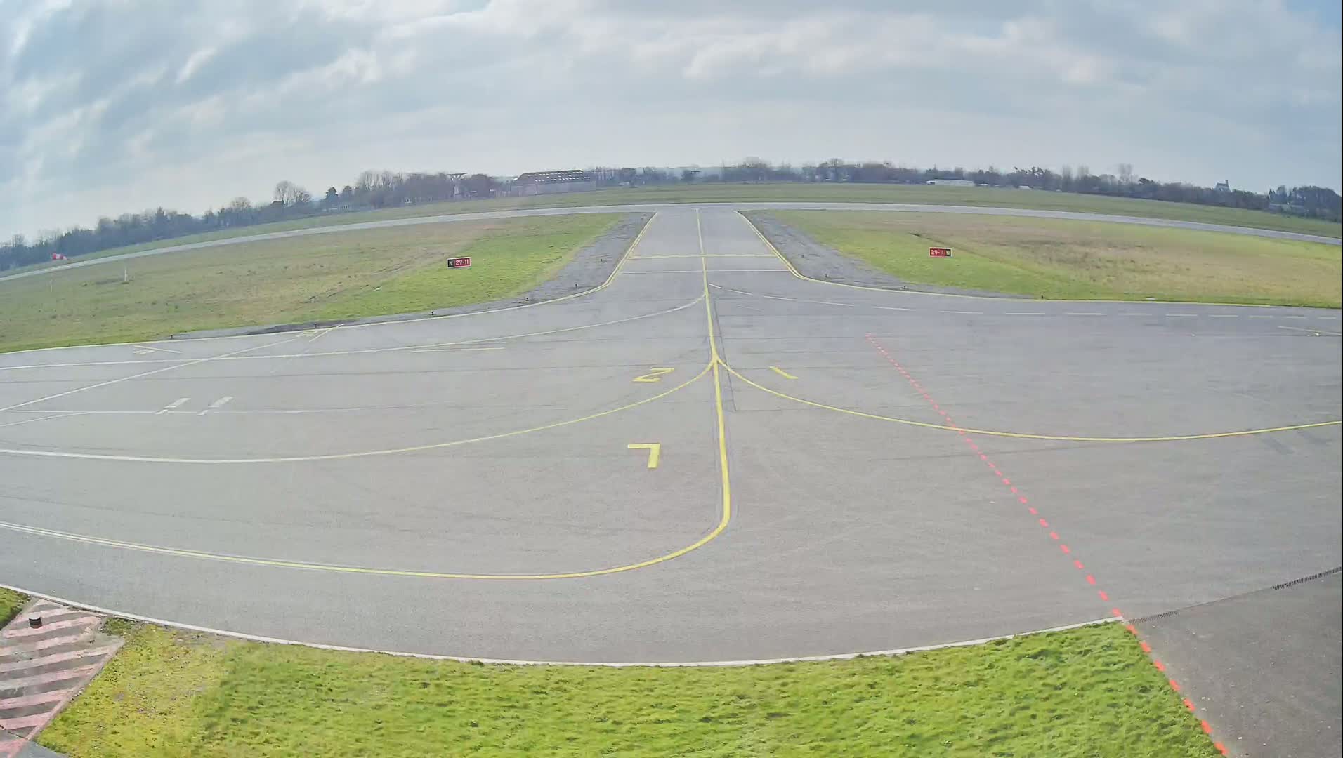 A runway at an airport under a cloudy sky.
