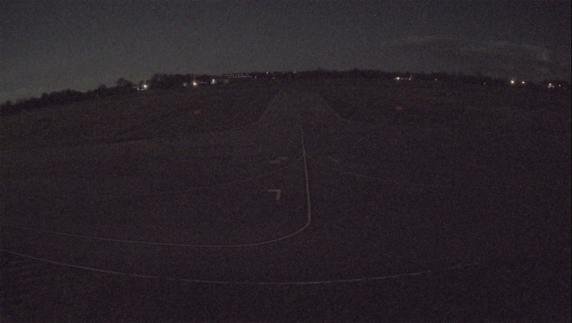 A dark asphalt runway is visible at night, with faint lights in the distance.
