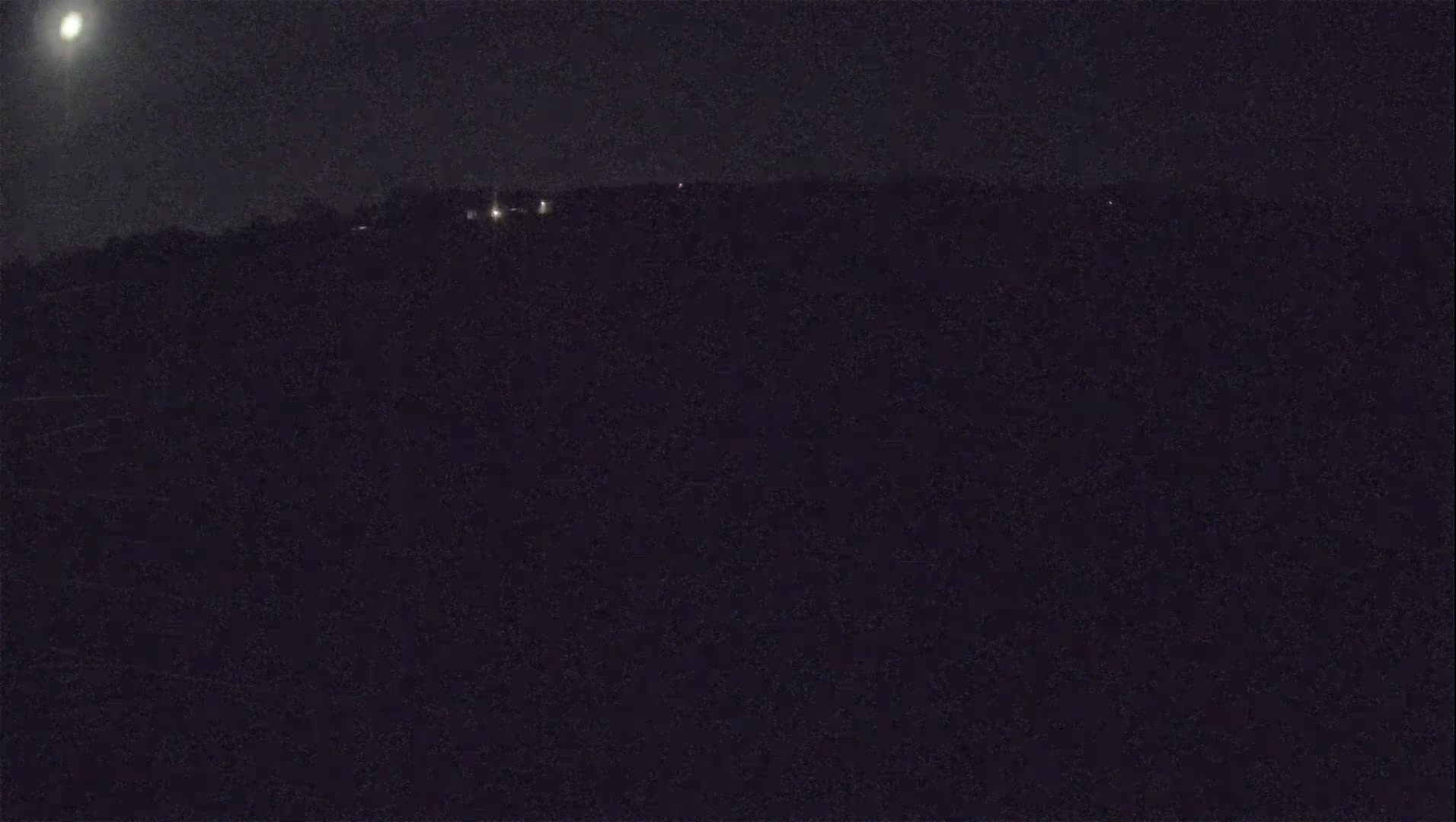 A nighttime, dark landscape is visible under a bright moon.