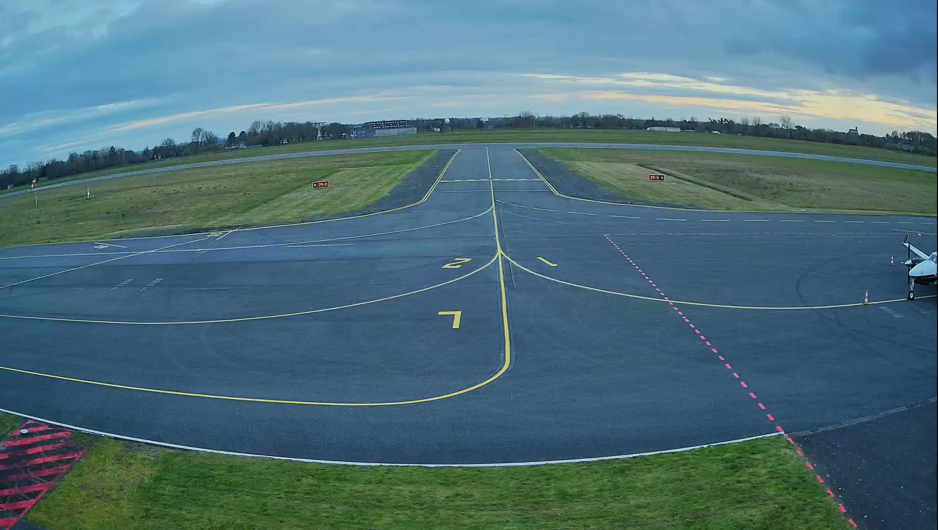 A small airplane is parked on the tarmac of an airport under a partly cloudy sky.