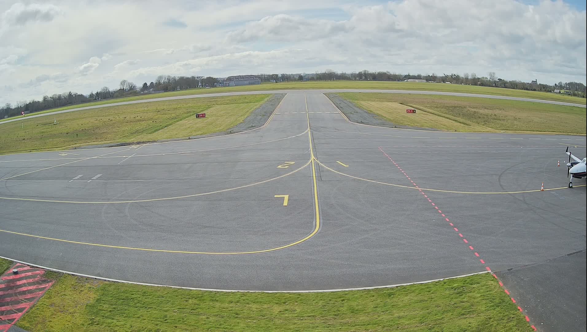 A small airplane is parked on the tarmac of an airport under partly cloudy skies.