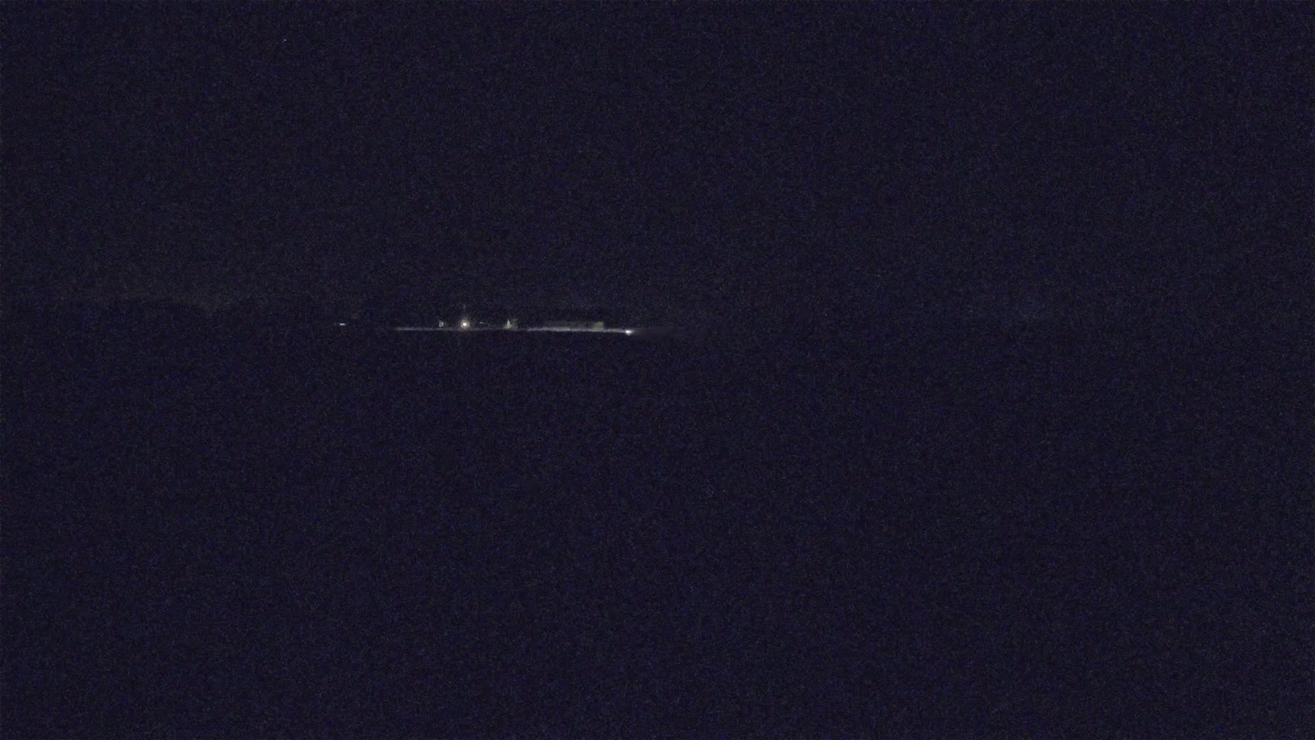 A long, low line of faint lights is visible in the distance on a very dark night.