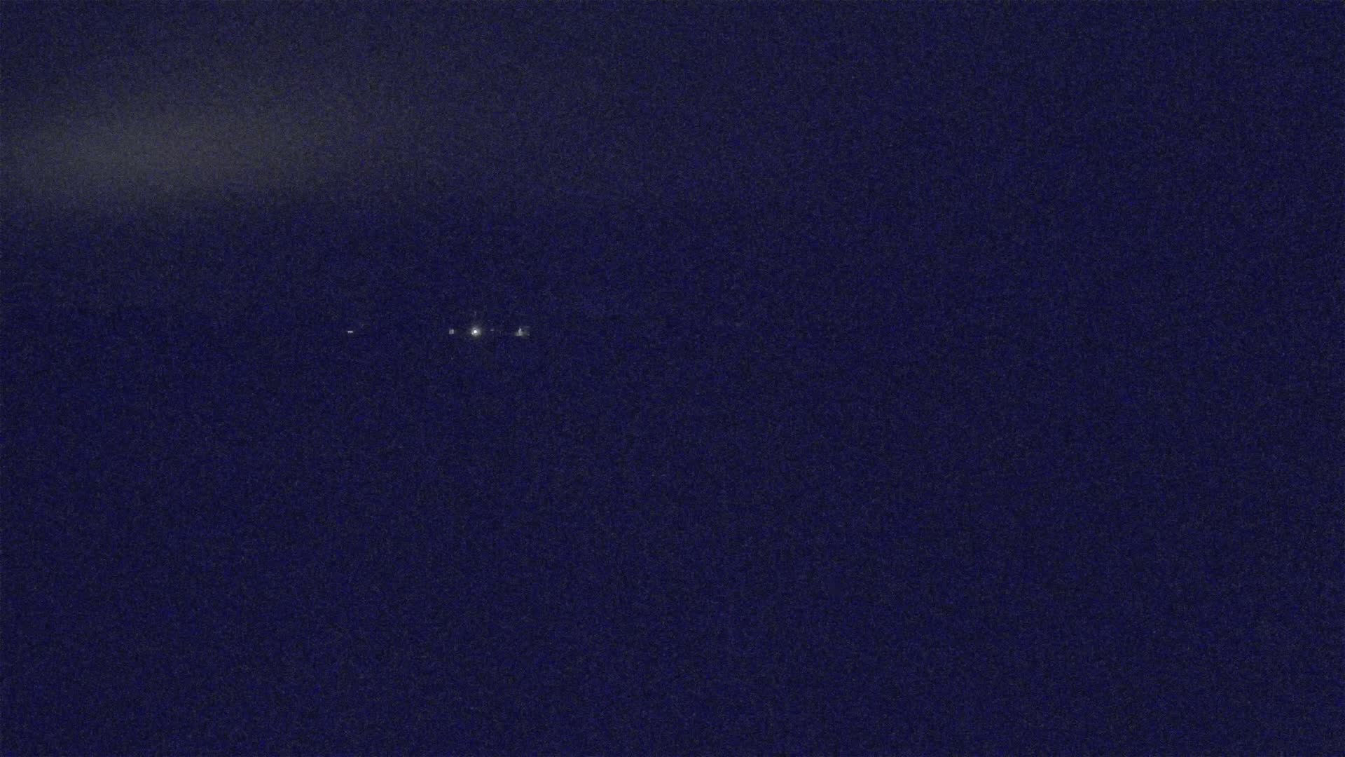 A dark blue night sky shows three small, distant lights.