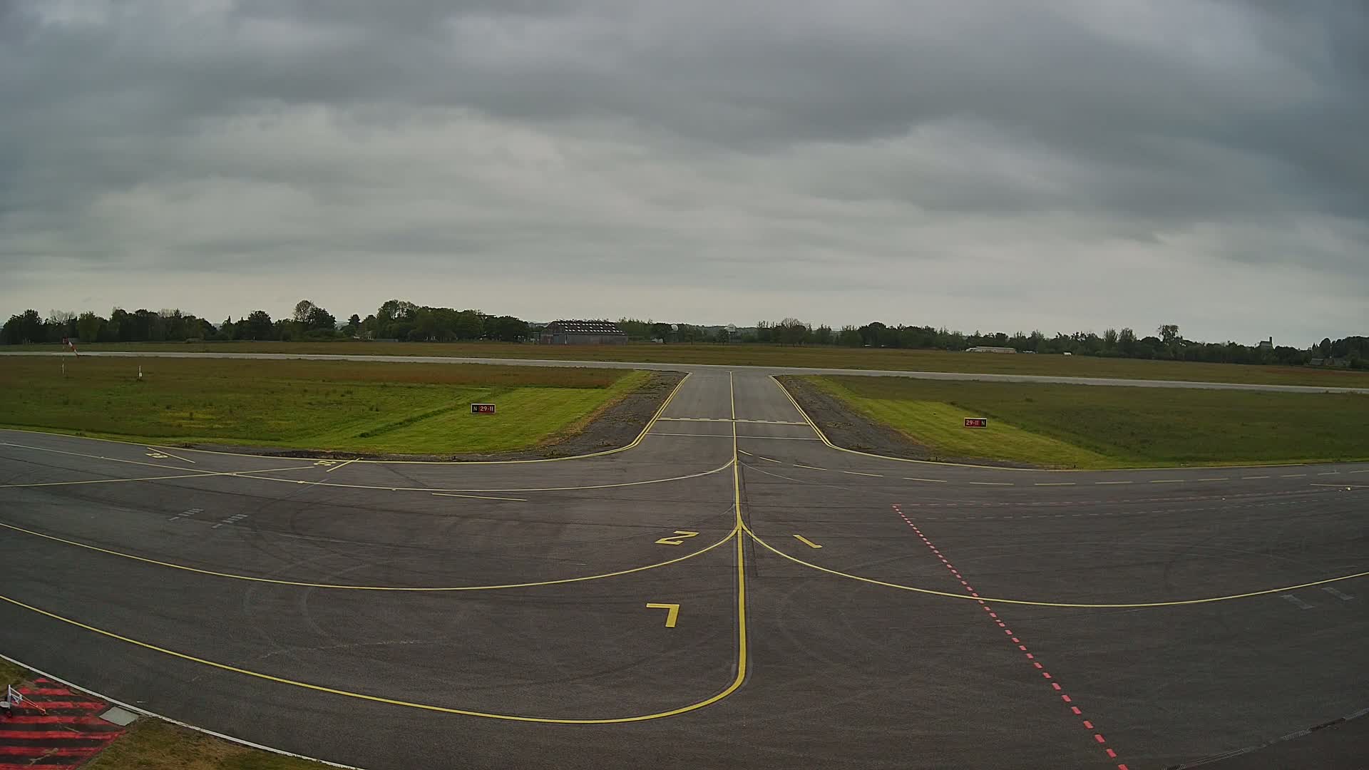 An airport runway and taxiway are visible under an overcast sky.