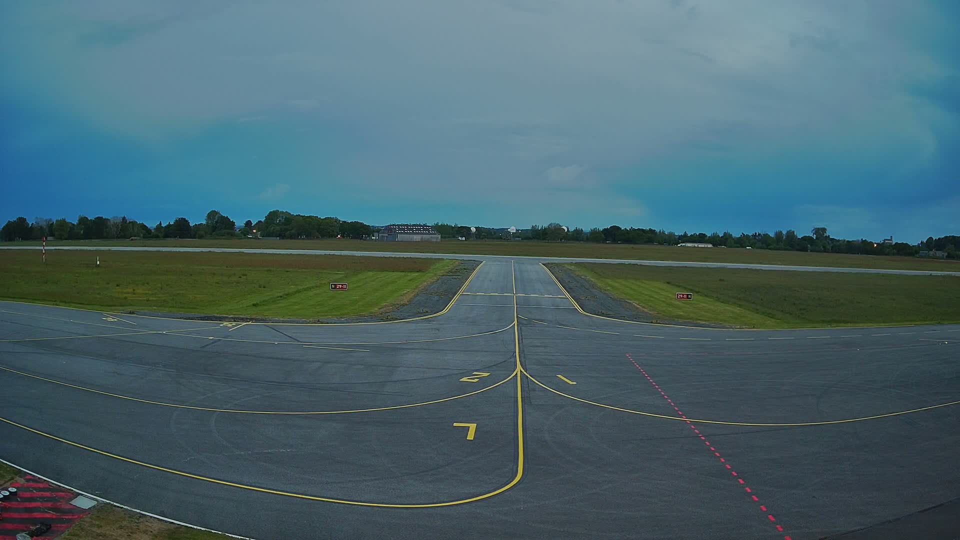A runway at a small airport under a cloudy sky.