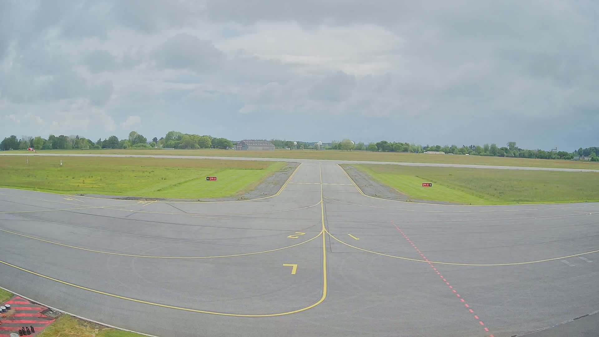 An airport runway with grassy areas on either side under an overcast sky.