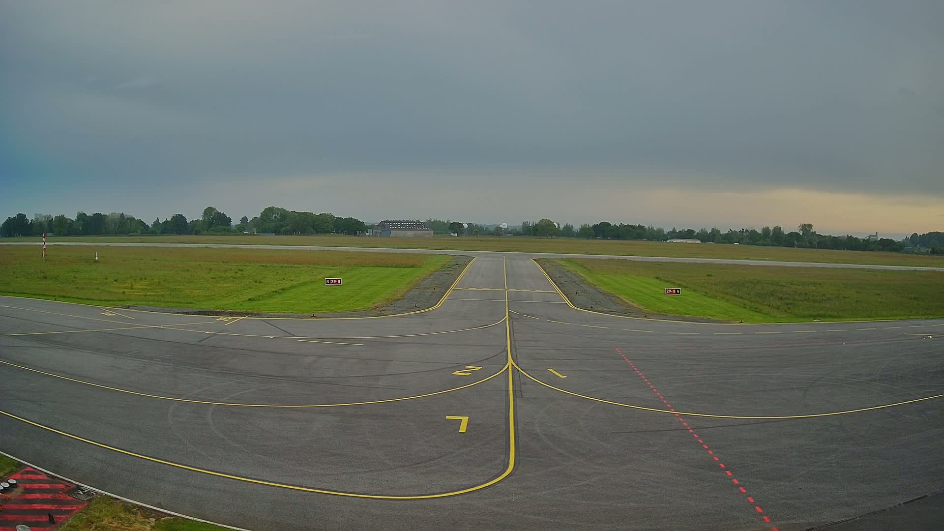 An airport runway with grassy areas on either side under an overcast sky.