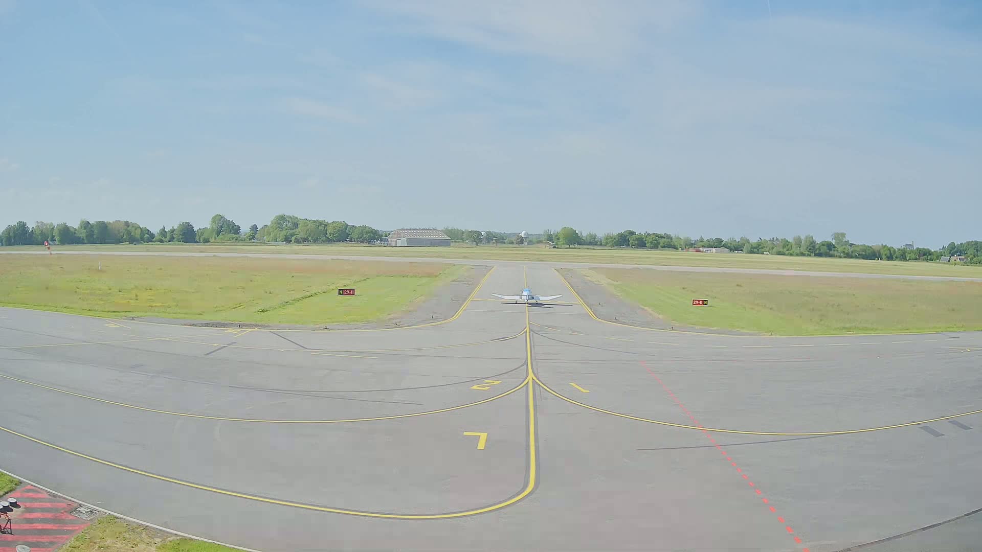 A small airplane sits on a runway at a small airport on a clear, sunny day.