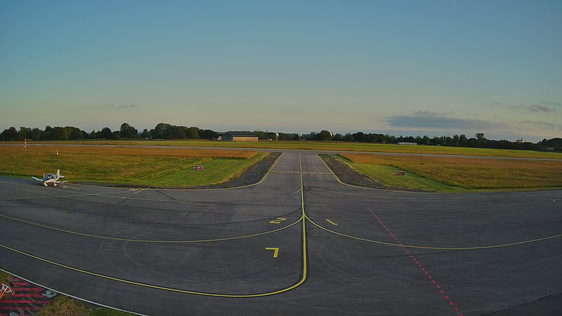 A small airplane sits on a tarmac at an airfield under a clear, twilight sky.
